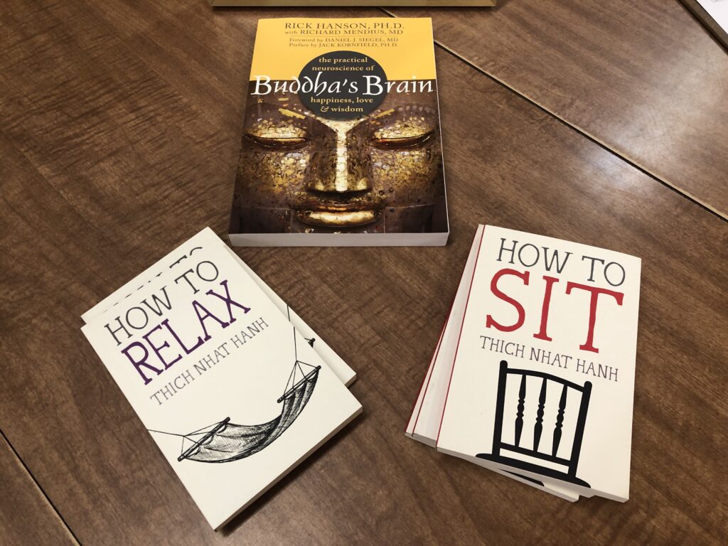 Three books on a table: Buddha's Brain by Rick Hanson, How to Relax and How to Sit both by Thich Nhat Hanh